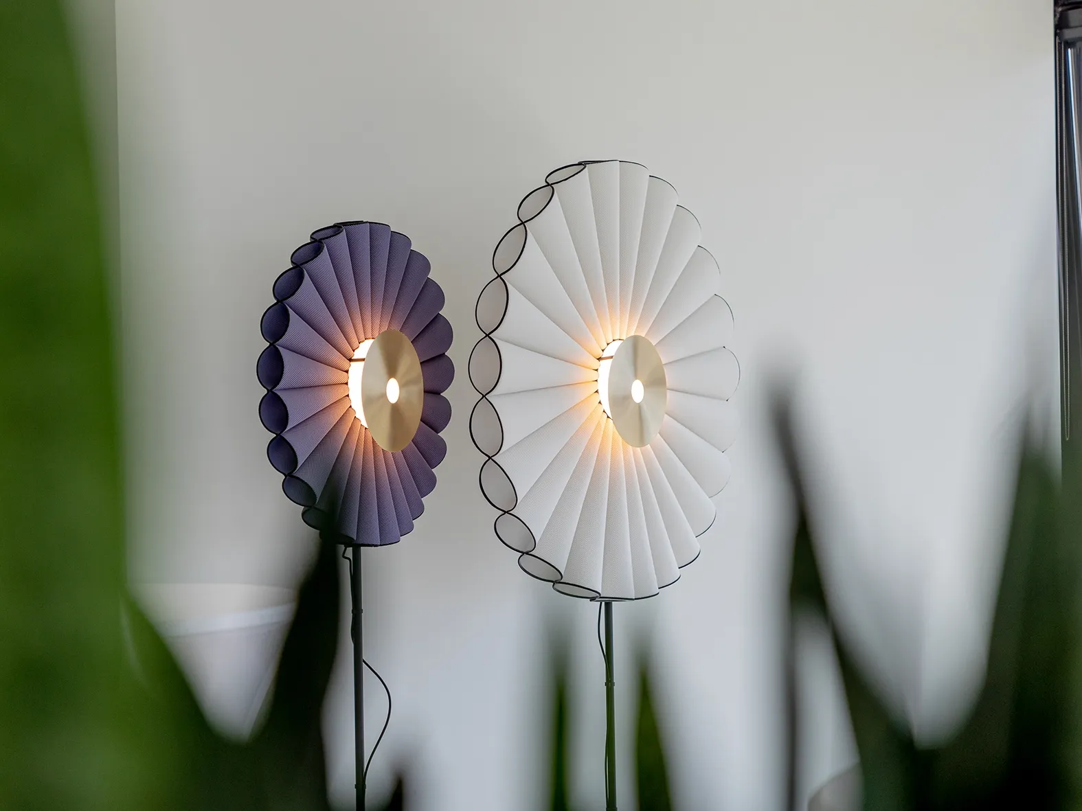 Zwei moderne Wandleuchten mit gefächertem Stoffdesign, die warmes Licht abstrahlen und eine stilvolle Atmosphäre schaffen.