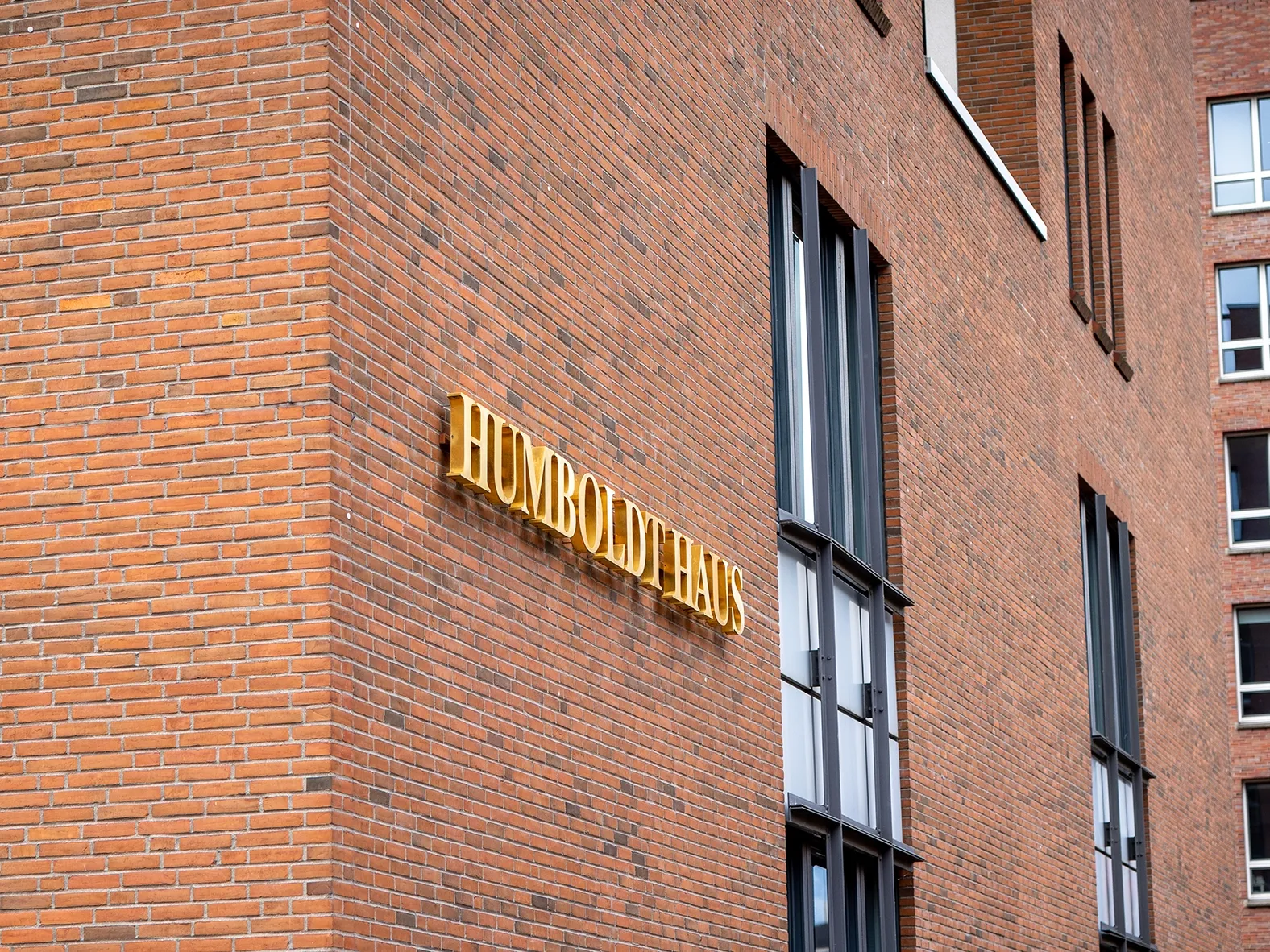 Backsteingebäude mit goldener Schrift „Humboldthaus“ an der Fassade und großen Fenstern in modernem Stil.