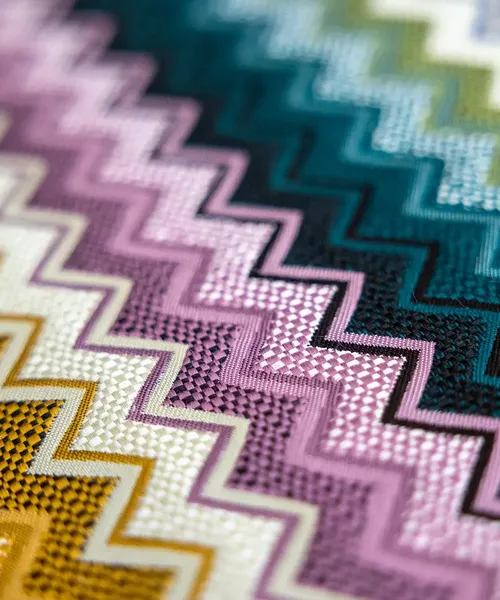 Nahaufnahme eines bunten Stoffmusters mit Zickzack-Design in verschiedenen Farben und Strukturen.