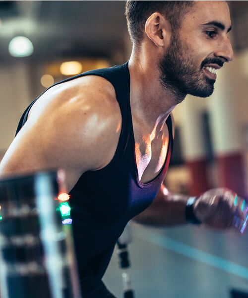 Sportlicher Mann trainiert intensiv in einem Fitnessstudio, mit Fokus auf seine Arme und Schultern.