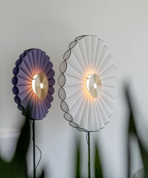 Zwei moderne Wandleuchten mit gefächertem Stoffdesign, die warmes Licht abstrahlen und eine stilvolle Atmosphäre schaffen.