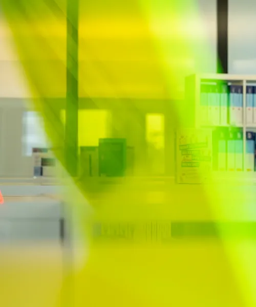 Bunte Bücherregale in einer modernen Bibliothek, im Vordergrund durchsichtige gelbe und orangefarbene Acryl-Elemente.