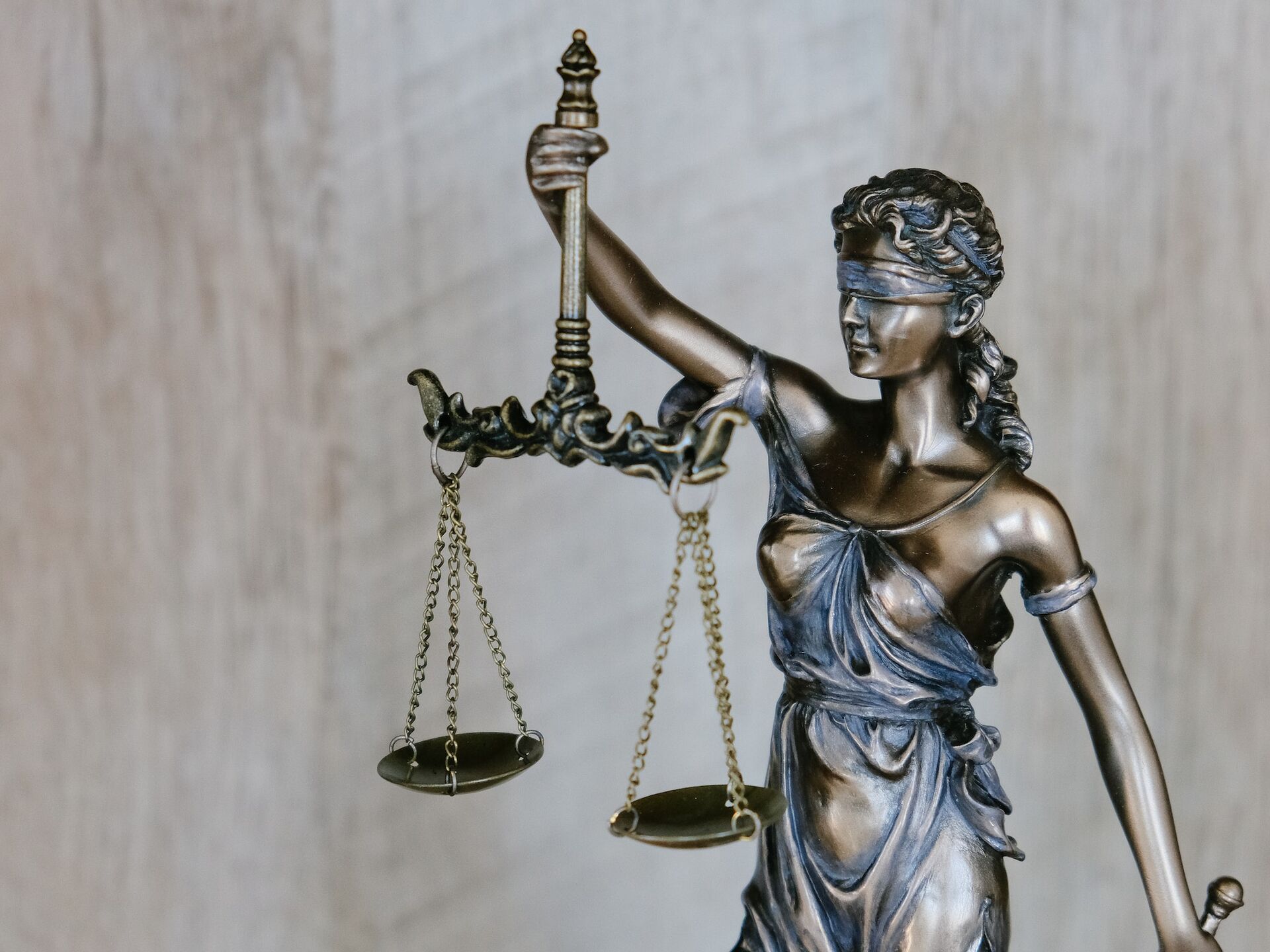 Bronzestatue der Justitia mit Augenbinde und Waage als Symbol für Gerechtigkeit und Gleichheit.