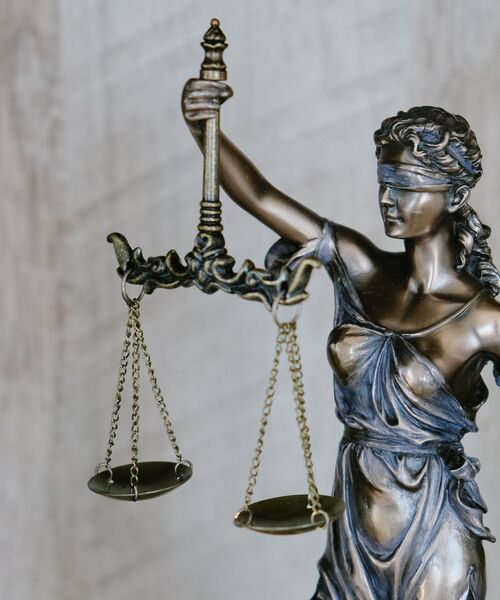 Bronzestatue der Justitia mit Augenbinde und Waage als Symbol für Gerechtigkeit und Gleichheit.