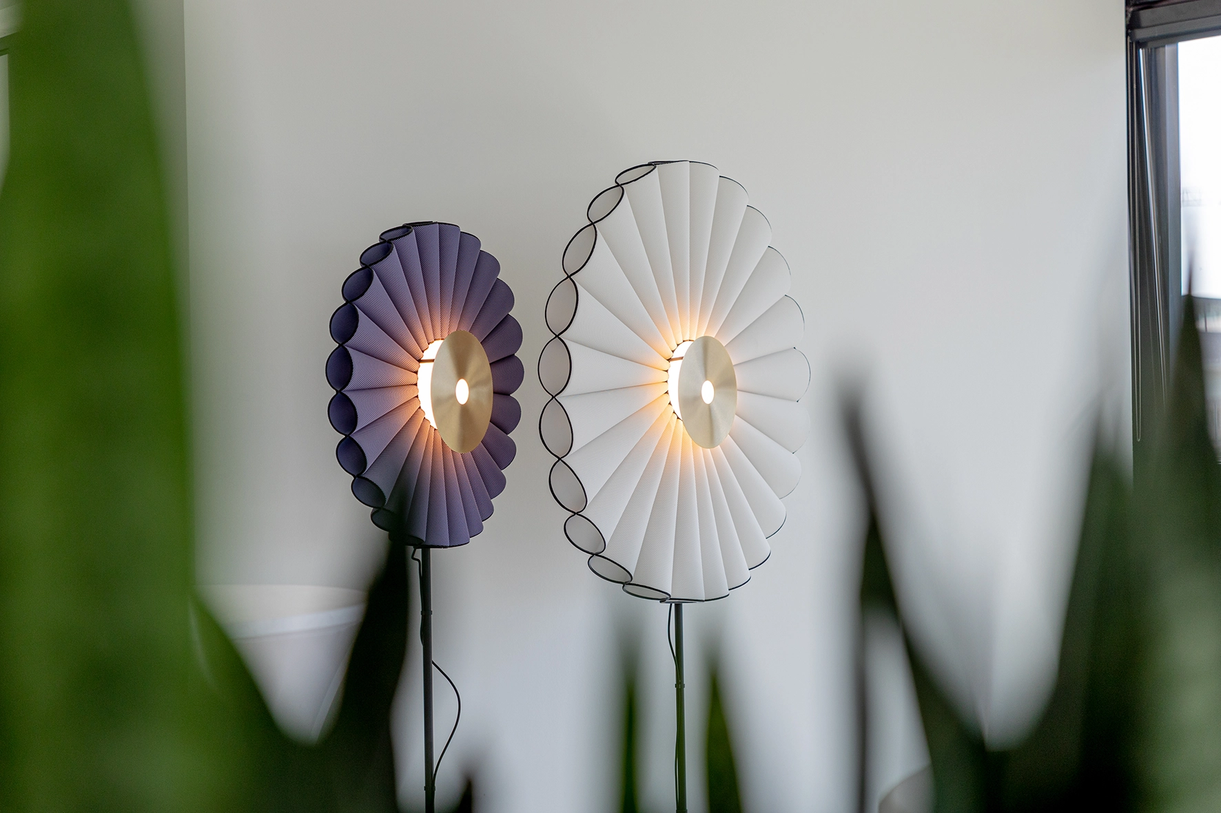 Zwei moderne Wandleuchten mit gefächertem Stoffdesign, die warmes Licht abstrahlen und eine stilvolle Atmosphäre schaffen.